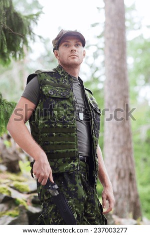 hunting, war, army and people concept - young soldier, ranger or hunter with knife in forest