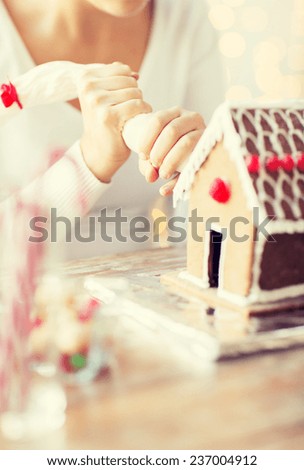 cooking, people, christmas and decoration concept - close up of woman making gingerbread houses at home