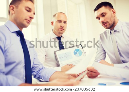 business, office and people concept - serious businessmen with papers in office
