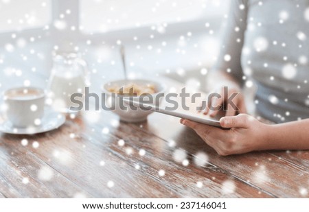 health, technology, internet, food and home concept - close up of woman with tablet pc computer screen sitting at table and having breakfast