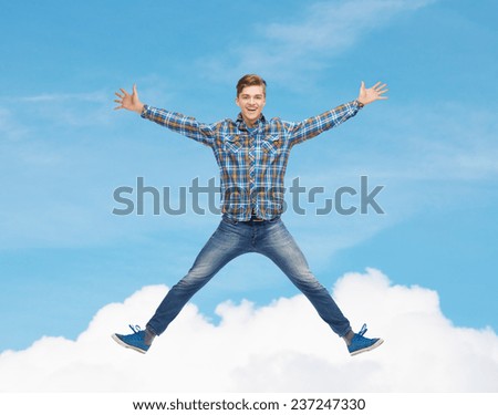 happiness, freedom, movement and people concept - smiling young man jumping in air over blue sky with white cloud background