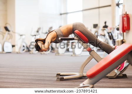 sport, training, fitness, lifestyle and people concept - young woman flexing back muscles on bench in gym