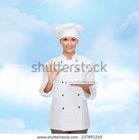 cooking, technology and people concept - smiling female chef, cook or baker with tablet pc computer over blue cloudy sky background