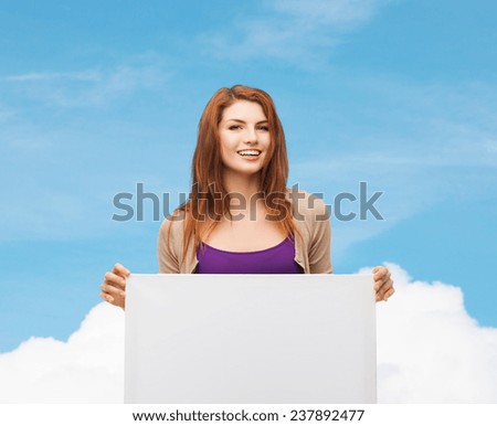advertising, education and people concept - smiling teenage girl with blank white board over blue sky and cloud background