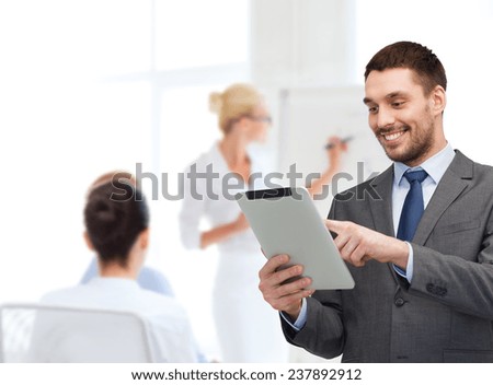 business, people, technology and teamwork concept - smiling young businessman with tablet pc computer over business team in office background