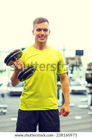 sport, fitness, lifestyle and people concept - smiling man with dumbbell in gym