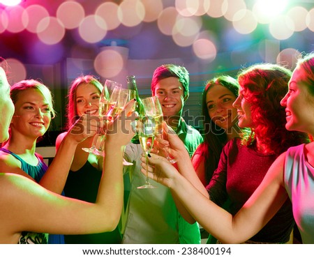 party, holidays, celebration, nightlife and people concept - smiling friends clinking glasses of champagne and beer in club