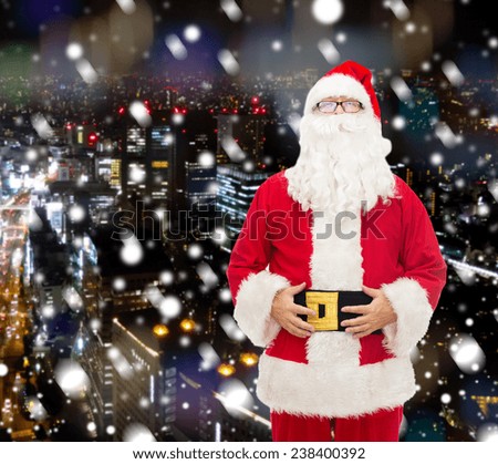 christmas, holidays and people concept - man in costume of santa claus over snowy night city background