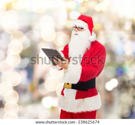 christmas, holidays, technology and people concept - man in costume of santa claus with tablet pc computer over lights background