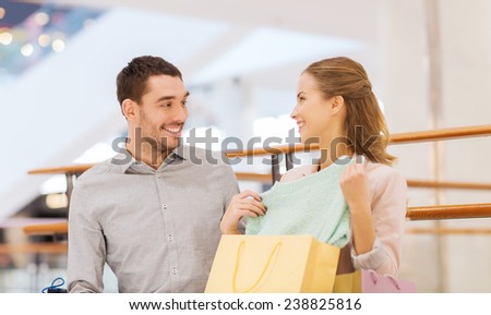 sale, consumerism and people concept - happy young couple showing content of shopping bags in mall