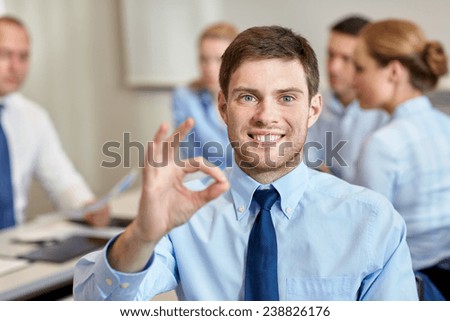 business, people, gesture and teamwork concept - smiling businessman showing ok gesture with group of businesspeople meeting in office