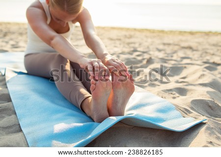 fitness, sport, people and lifestyle concept - close up of woman making yoga exercises on mat outdoors