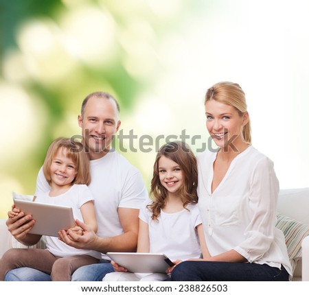 family, ecology, technology and people - smiling mother, father and little girls with tablet pc computers over green background