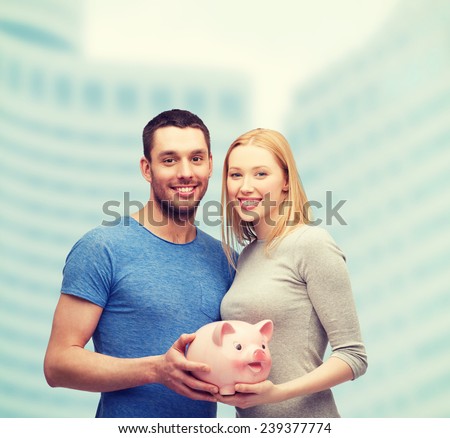 finance, money and family concept - smiling couple holding big piggy bank
