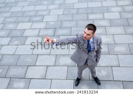 business, development and people and concept - young smiling businessman pointing finger outdoors from top