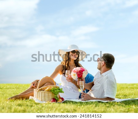 love, dating, people and holidays concept - smiling couple drinking champagne on picnic outdoors
