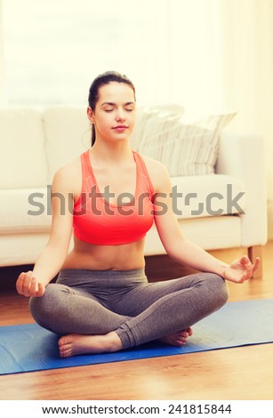 fitness, home and diet concept - smiling teenager meditating at home
