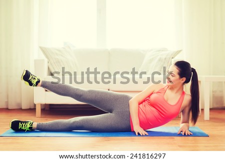 fitness, home and diet concept - smiling teenage girl doing exercise for legs on floor at home
