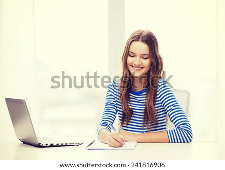 education, technology and home concept - smiling teenage girl with laptop computer, notebook and pen at home