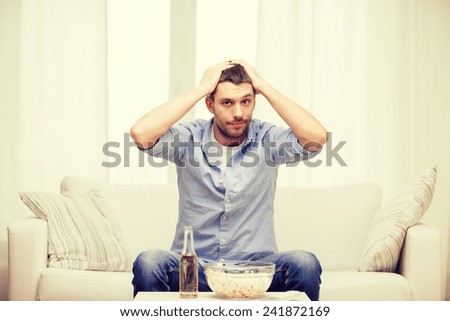 sports, happiness and people concept - sad man watching sports on tv and supporting team at home