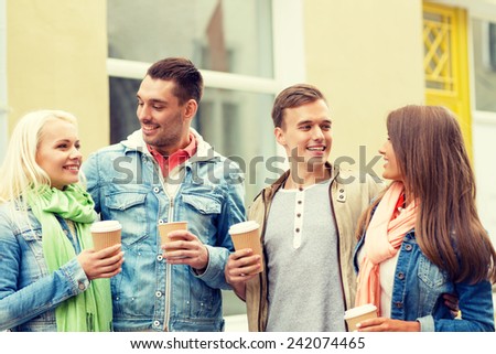 friendship, travel, drink and vacation concept - group of smiling friends with take away coffee