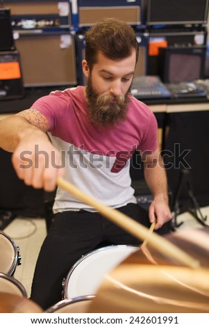 music, sale, people, musical instruments and entertainment concept - male musician playing cymbals at music store
