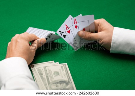 casino, gambling, poker, people and entertainment concept - close up of poker player with money holding playing cards at green casino table