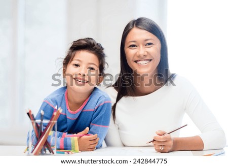 family, children and happy people concept - mother and daughter drawing