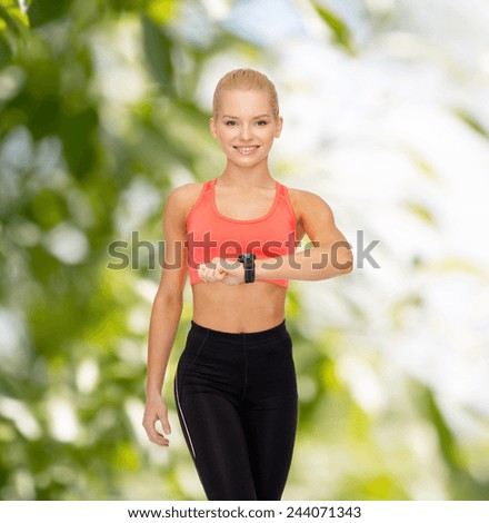 fitness, technology and exercising concept - smiling woman with heart rate monitor on hand