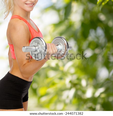 fitness, healthcare and exercise concept - close up of young sporty woman with heavy steel dumbbell