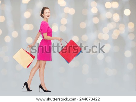 people, holidays and sale concept - young happy woman with shopping bags over holidays lights background