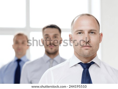 business and office concept - serious businessman in office with team on the back