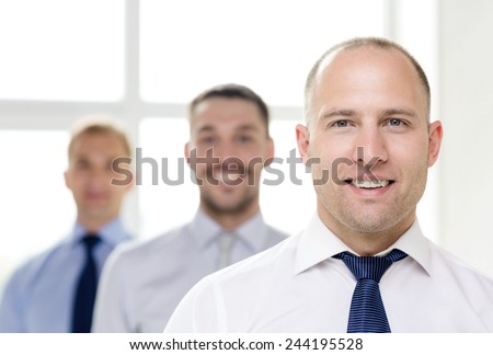 business and office concept - smiling businessman in office with team on the back