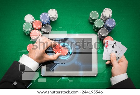 casino, online gambling, technology and people concept - close up of poker player with playing cards, tablet pc computer and chips at green casino table