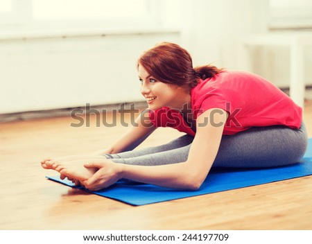 fitness, home and diet concept - smiling teenage girl streching on floor at home
