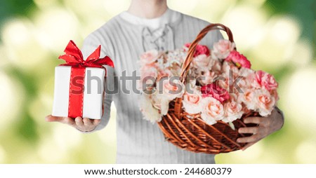 holidays, people, feelings and greetings concept - close up of man holding basket full of flowers and gift box over green background