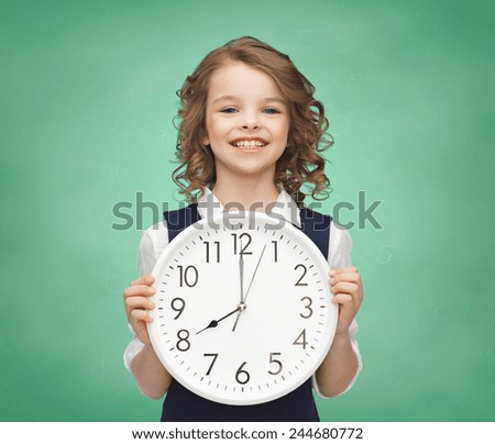 people, time management and children concept - smiling girl holding big clock showing 8 o\'clock