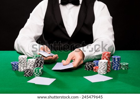 casino, gambling, poker, people and entertainment concept - close up of holdem dealer with playing cards and chips on green table