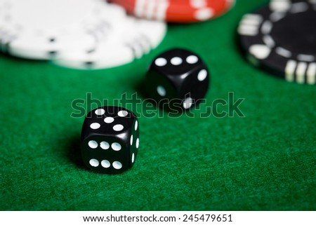gambling, fortune, game and entertainment concept - close up of black dices on green casino table