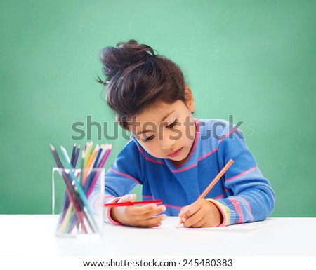 children, hobby, childhood and happy people concept - little girl drawing over green chalk board background