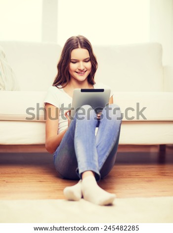 home, technology and internet concept - smiling teenage girl sitting ong the floor with tablet pc computer at home