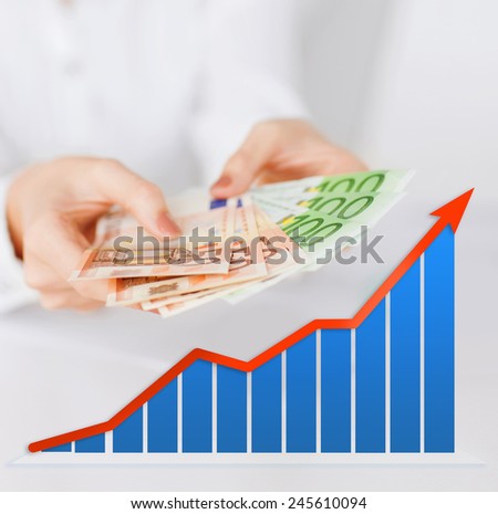 business, people and finances concept - close up of woman hands holding euro money over gray background with growth chart