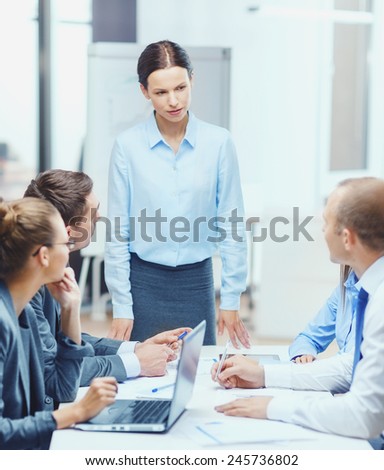 business, technology, people and management concept - strict female boss talking to business team in office