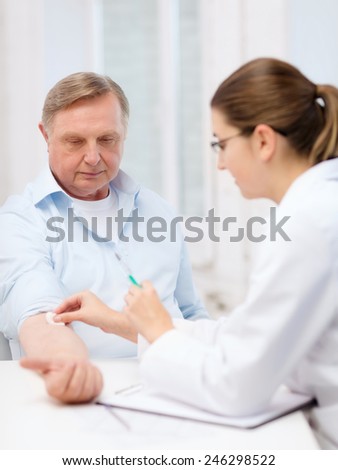 healthcare, medicine and elderly concept - female doctor or nurse doint injection to old man