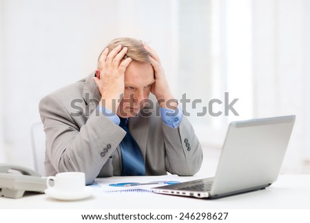 business, technologym communication and office concept - upset older businessman with laptop, charts, coffee and telephone in office