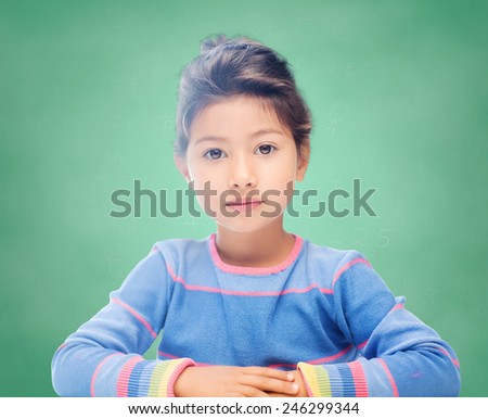education, school and children concept - little student girl over green chalk board background