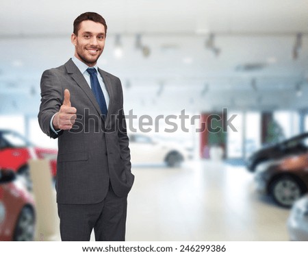 auto business, car sale, gesture and people concept - smiling businessman showing thumbs up over auto show background