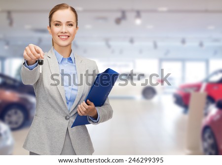 auto business, car sale, gesture and people concept - happy businesswoman or saleswoman with folder giving car key over auto show background