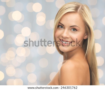 people, beauty, body and skin care concept - beautiful woman face and hands over holidays lights background