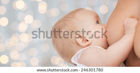 motherhood, children, people and care concept - close up of mother breast feeding adorable baby over holidays lights background